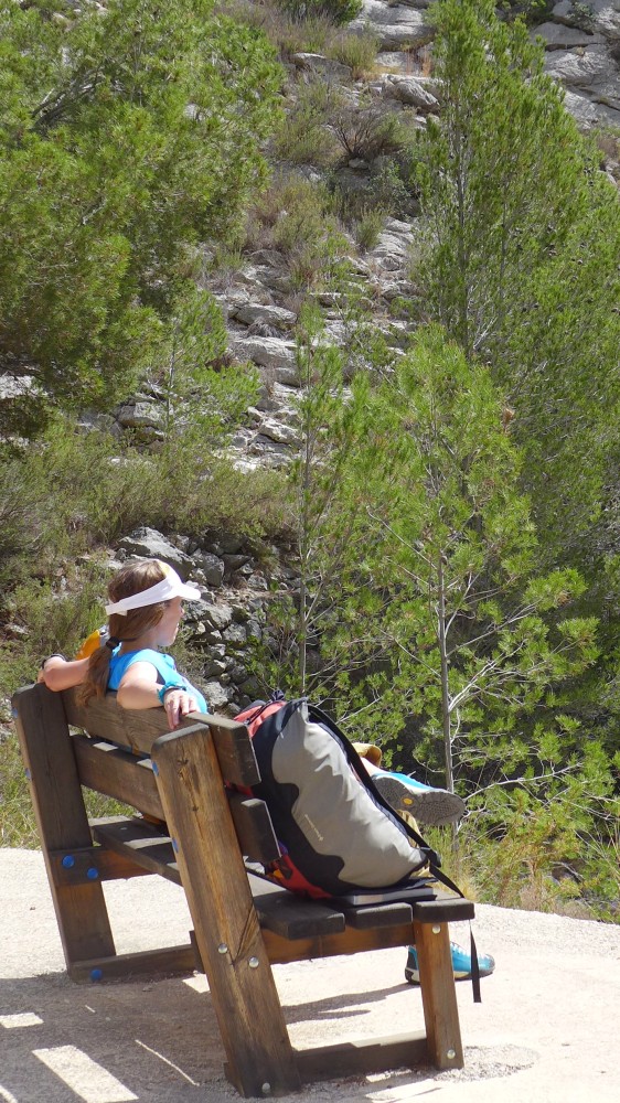 Person sat on a bench looking at the scenery, climbing bag next to them